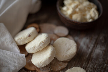 Raw cottage cheese pancakes (syrniki) with raisins, dusted with flour, arranged on a rustic wooden...