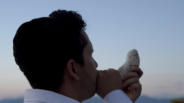 Jewish man blows horn or shofar to celebrate Hebrew religious holidays
