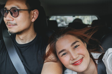 Fototapeta premium Happy asian Thai couples traveling by car, man driving and woman taking selfie together, lovers trip.