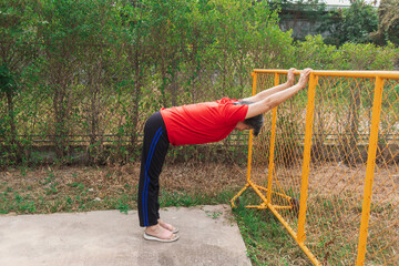 Fototapeta premium Happy asian old woman stretching arms and body at park in morning after exercise, wear red t-shirt, healthy routine.
