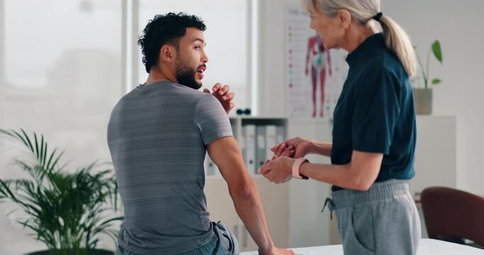 Chiropractor, patient and talking with shoulder for consultation, injury or muscle recovery at clinic. Physiotherapist, client or physio helping with sore tension, ache or sprained joint at practice