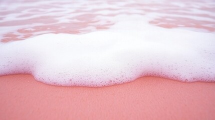 Fototapeta premium Soft Pink Sand and Foamy Waves at Sunrise on a Tranquil Beach