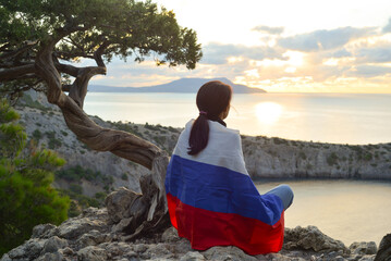 Young traveler with the Russian flag on her shoulders on the top of Karaul-Oba mountain, Novy Svet...