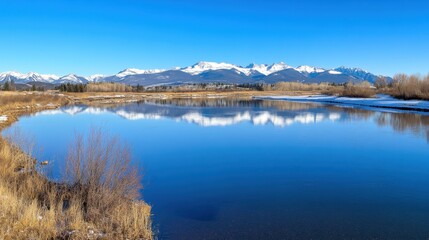 Fototapeta premium Serene Mountain Reflection in a Calm Lake Under Clear Blue Sky