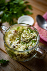 Chicken soup with onion and egg in a beautiful plate on a wooden table for lunch. Onion soup with egg for dinner. Close-up. Vertical photo.