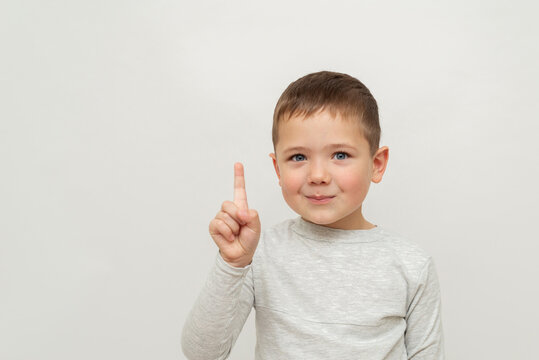 portrait of a five year old child on a white background. little boy showing 1 index finger, finger sign - attention