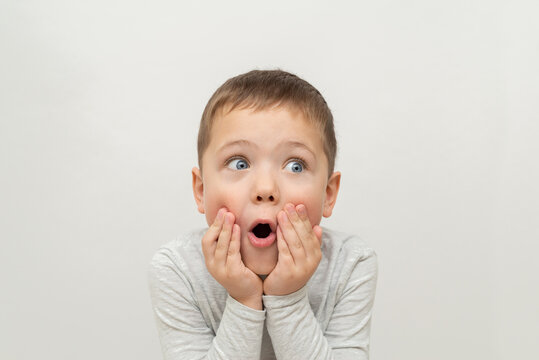 Naklejki portrait of a child on a white background. surprised little boy with blue eyes, emotion of surprise and surprise