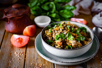 Hearty lunch: Lentils with chicken and vegetables in a beautiful plate on a wooden table. Home cooking. Close-up.