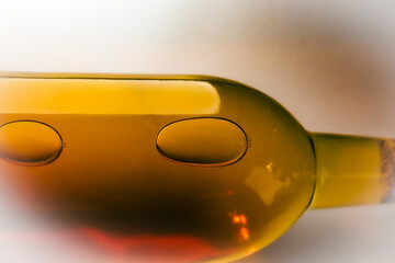 abstract close-up of white wine bottle amber glass containing liquid with bubble surface tension art isolated on white background