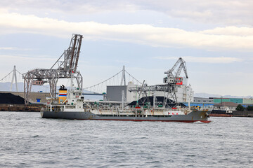 Container port at Osaka Japan, Large crane works on large coal stockpile at Osaka port. Cargo transportation and activity at modern shipping container terminal.