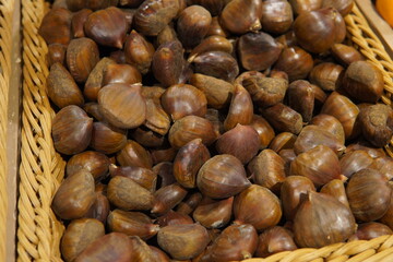 Fresh edible chestnuts in a wicker basket. Brown tones of chestnuts. Seasonal product, natural food, autumn harvest