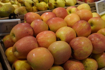 Fresh apples of different varieties. Red, green and yellow fruits are neatly laid out on the store counter, creating a bright and appetizing composition.