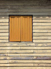 dusty yellow ancient wooden building facade with beautiful brown wooden windows.