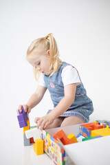 Educational Toys: The Child Develops Motor Skills With The Help Of Colorful Cubes on a white background. The girl is playing with cubes