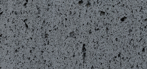 Panoramic background of dark gray volcanic stone wall texture with a porous surface