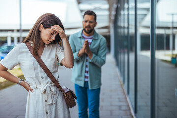 Man Apologizing to Upset Woman Outdoors in a Modern Urban Setting