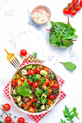 Quinoa salad with tomatoes, paprika, avocado, cucumbers and parsley. White table background, top view