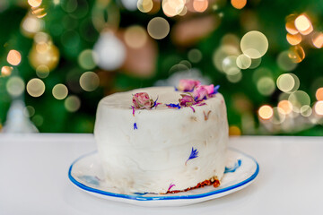 A cake on the background of a Christmas tree, a festive atmosphere of the new year