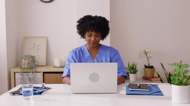 Happy young Latin American medical professional working on laptop computer at doctor's office. Health and medicine concept.