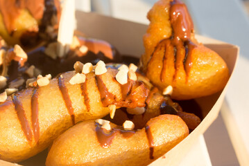 Greek lukumades donuts with pistachio-nut sauce sauce in a cardboard tray. street food, fast food.