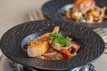 Grilled salmon and fettuccine. Italian fettuccine with salmon and herbs. Spaghetti salmon steak and herbs in Black plate. grilled salmon fillet with spaghetti