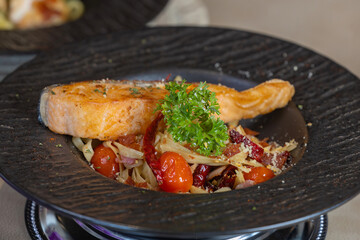 Grilled salmon and fettuccine. Italian fettuccine with salmon and herbs. Spaghetti salmon steak and herbs in Black plate. grilled salmon fillet with spaghetti