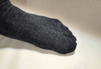 Close-up of a dark gray thick sock on a foot