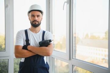 Construction worker repairing plastic window with screwdriver indoors, space for text.