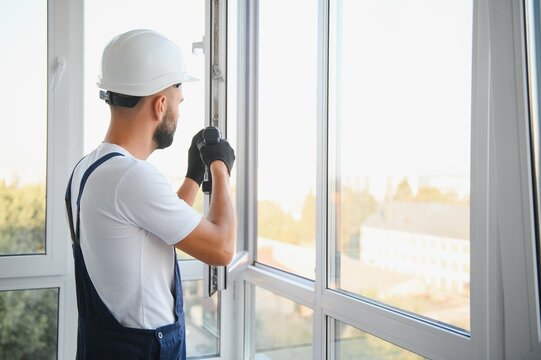 Construction worker installing window in house. Handyman fixing the window with screwdriver