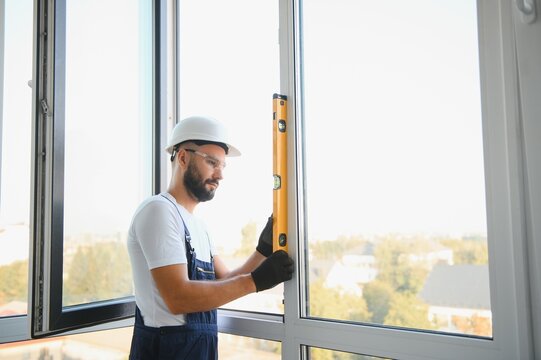 handsome young man installing bay window in new house construction site