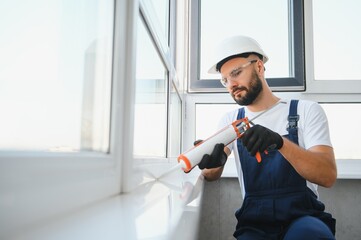 Hands applying silicone sealant that defending from water leaks and mildew. Home repair and...