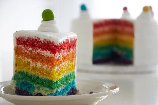 Close-up of a rainbow sponge cake and a slice of cake on a plate