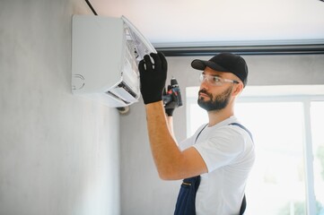 Happy Male Technician Repairing Air Conditioner