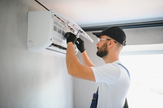 Repairman fix air conditioning systems, Male technicians service for repair and maintenance of air conditioners, Air conditioning technicians install new air conditioners in homes