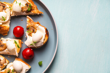 Mini toast with cottage cheese, quail eggs, cherry tomatoes, mushrooms and microgreens on a blue plate. Copyspace