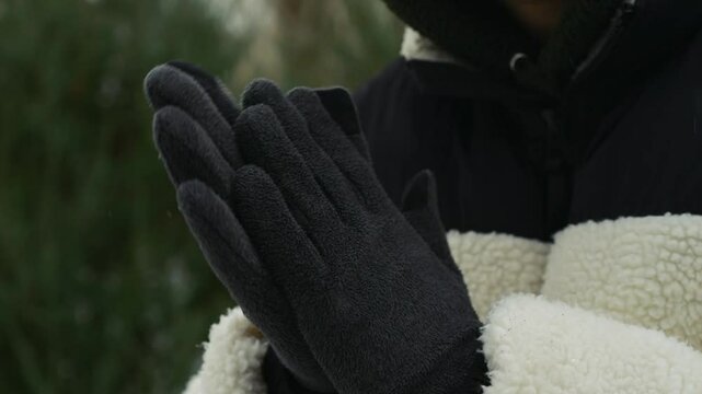The man wearing gloves suffered frostbite on his hands.
Man's hands are frozen in winter.
The guy warms his palms.
A man's hands are frozen on the street during a snowfall.
Snowfall outside.
Cold