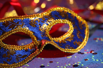 Beautiful carnival mask and confetti on color background, closeup