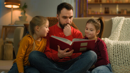 Caucasian family late night evening at home parent dad father man reading book kids watching photo...