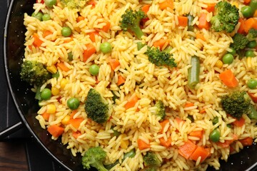 Tasty rice with vegetables in baking dish on table, top view