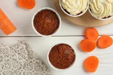 Tasty carrot muffins with cream and fresh vegetable on white wooden table, flat lay