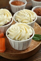Tasty carrot muffins and fresh vegetable on wooden table, closeup