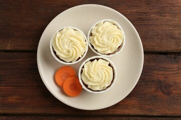 Delicious carrot muffins and fresh vegetable on wooden table, top view