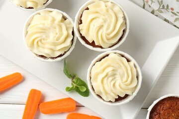 Delicious carrot muffins with fresh vegetables and mint on white wooden table, flat lay