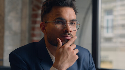 Pensive guy Arabian Indian business man thinking looking at camera close up male thoughtful puzzled businessman office think question idea solution problem search choose decide consider ponder serious