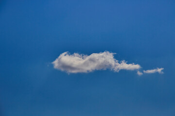 One white cloud in a clear blue sky.