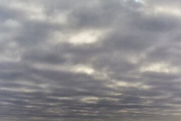 Dark gray sky with rare white patches of sunlight in winter. soft focus, blur