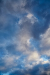 Soft sunlight highlights gray winter clouds against a bright blue sky. blur