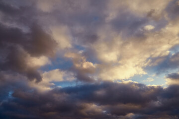 Changing weather: sun glimmers on gray clouds in the blue sky.