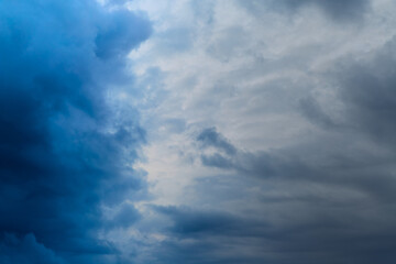 Dark gray and blue clouds collide in the sky, meeting of two weather fronts, impending storm, weather change, winter sky.