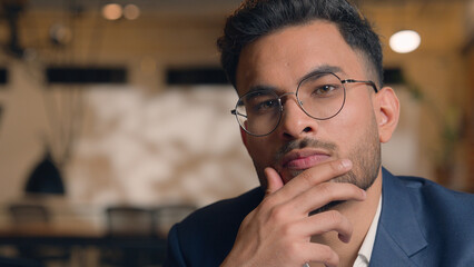 Pensive guy Arabian Indian business man thinking looking at camera close up male thoughtful puzzled...